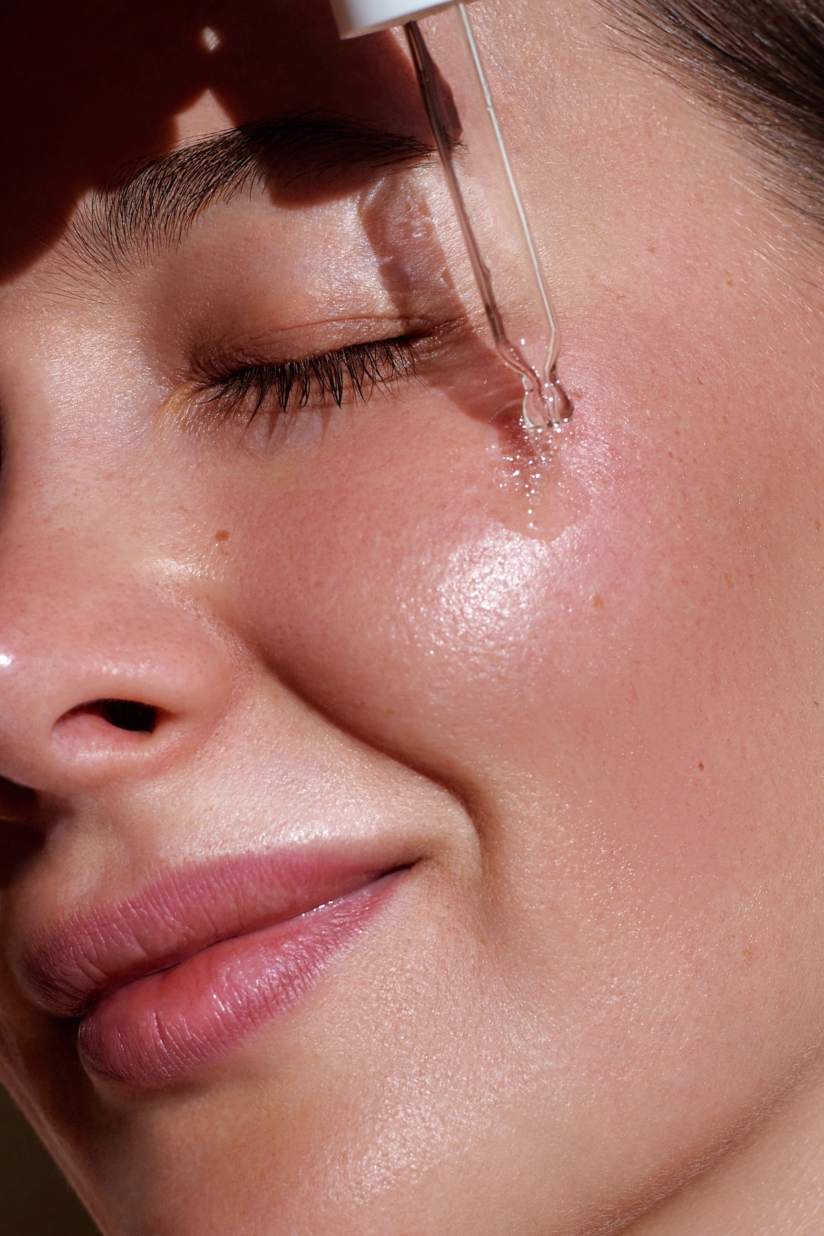 woman applying serum to her face